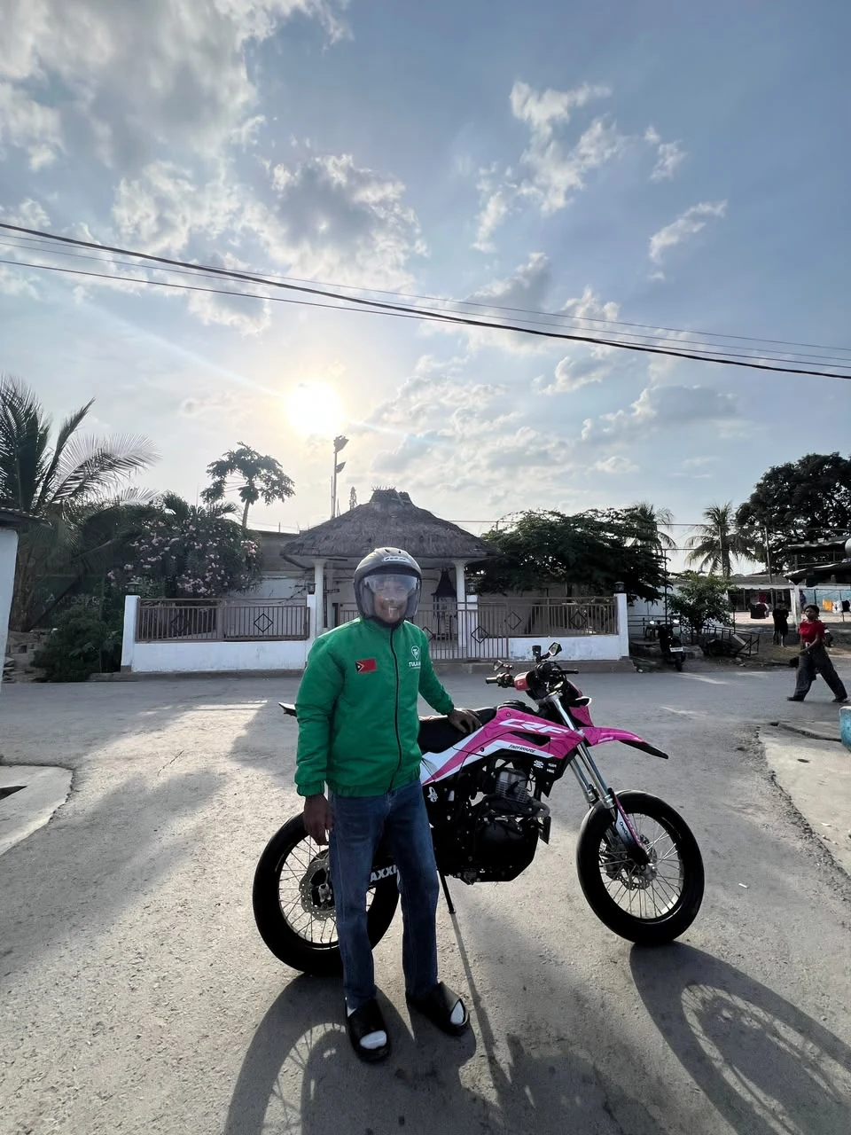 A TULA-HAU driver standing with a pink motorbike on a street