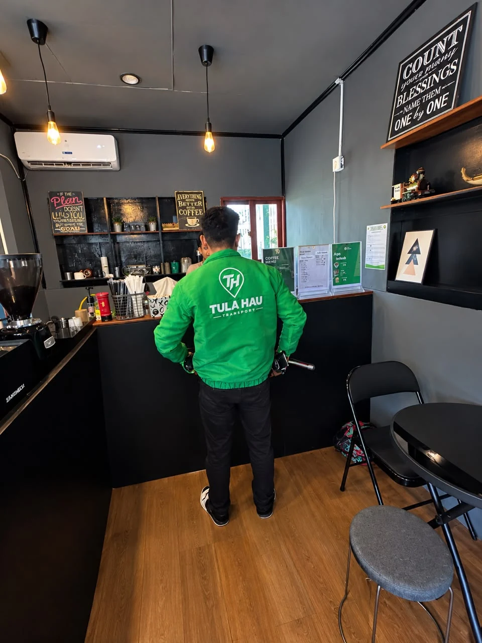 A TULA-HAU driver in a green jacket inside a café